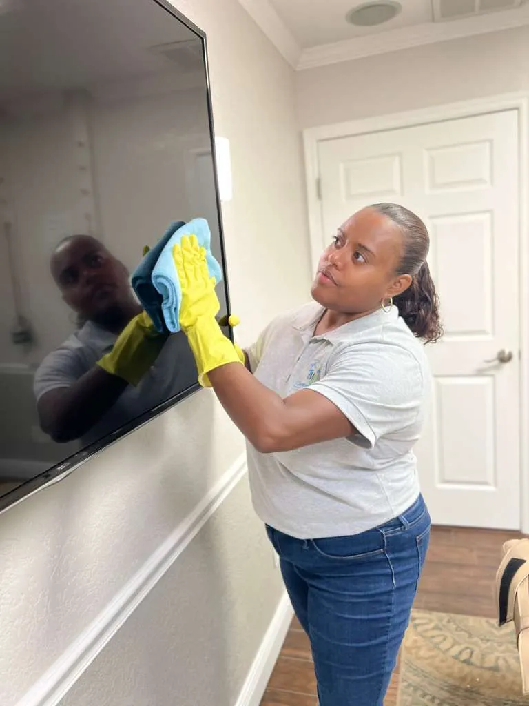 Mical Johnson cleaning a television screen in a professional office.